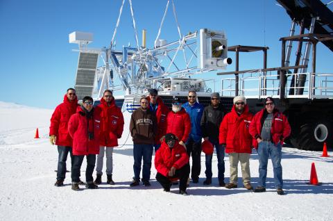 Group of people in Antarctica stand in front of large telescope.